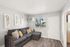 Bright, cozy living room with modern grey couch, stylish feather artwork, and large window inviting natural light.