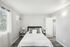 Bright and airy bedroom with modern decor, featuring a cozy bed, sleek nightstands, and a view of lush greenery through large windows.