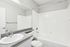 Bright and modern bathroom featuring a sleek white bathtub, large mirror, and elegant gray countertop.