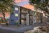 Charming three-story apartment building with modern exterior, nestled amid lush trees and highlighted by a vibrant sunset sky.