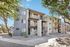 Charming three-story apartment building with outdoor stairs, nestled among trees and landscaped surroundings.