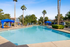 Lush apartment complex with a sparkling pool, surrounded by tall palm trees and cozy cabanas.