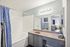 Contemporary bathroom with elegant features, including a chic vanity, large mirror, and inviting bathtub, highlighted by stylish blue accents.