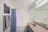Bright and modern bathroom featuring a sleek countertop, stylish blue geometric shower curtain, and elegant lighting.