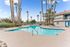 Inviting apartment community pool area with sparkling water, surrounded by tropical palm trees and modern amenities, perfect for relaxation and enjoyment.