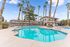 Inviting apartment complex showcasing a sparkling swimming pool, surrounded by palm trees and modern buildings.