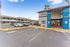 Inviting apartment complex with a vibrant leasing center and ample parking under a clear blue sky.