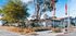 Charming apartment community with lush landscaping, vibrant flags, and modern leasing office under a clear blue sky.