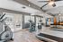 Luxury apartment gym adorned with modern exercise equipment, including treadmills, stationary bikes, and stylish mirrored walls, offering a bright and motivating workout space.