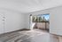 Bright living room with sleek wood flooring and large sliding glass doors leading to a cozy outdoor patio.