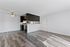 Bright open-plan apartment featuring a sleek kitchen, inviting ceiling fan, stylish flooring, and ample natural light.