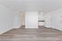 Modern open-plan apartment with sleek wood flooring, a chic white kitchen, and abundant natural light.