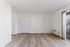 Bright and airy apartment interior featuring sleek hardwood floors, a modern white refrigerator, and ample natural light through sliding glass doors.
