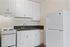 Modern kitchen with sleek white cabinets, spacious countertop, and essential appliances for a stylish culinary space.