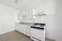 Bright, minimalist kitchen with sleek white cabinetry and modern gas stove, perfect for culinary creativity.