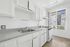 Bright and airy kitchen with modern white cabinets, sleek countertops, and a large window offering a stunning urban view.