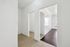 Bright and inviting hallway featuring crisp white walls, leading to a spacious room with elegant wood flooring, offering modern living charm.