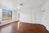 Bright and inviting empty room featuring elegant wood flooring, ample natural light from large windows, and a minimalist white interior.
