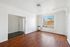 Bright, spacious living room with elegant wood floors, large window with a city view, and modern minimalist design.