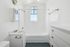 Bright, minimalist bathroom featuring a sleek white tub and vintage fixtures beneath a charming arched ceiling.