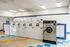 Bright and clean laundry room featuring multiple washing machines and dryers, with colorful floor tiles creating a welcoming atmosphere.
