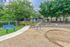Inviting apartment playground surrounded by lush trees, featuring a blue bench and playful outdoor structures.