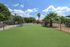 Inviting outdoor space with lush green lawn, tall palm trees, and a clear blue sky, perfect for relaxation and leisure activities.