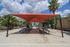 Charming outdoor communal space with shaded picnic tables, surrounded by lush palm trees and clear blue skies.