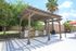 Charming outdoor pavilion with modern grills and lush greenery, perfect for sunny day barbecues.
