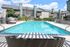 Inviting outdoor pool in a modern apartment complex, surrounded by lush greenery and stylish loungers, perfect for relaxation and leisure.