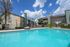 Inviting apartment complex with a refreshing outdoor pool, surrounded by modern buildings under a clear blue sky.