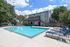 Inviting outdoor pool area with modern loungers and lush greenery, perfect for relaxing under sunny skies.