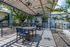 Inviting outdoor patio with modern seating under a stylish pergola, surrounded by lush greenery in a charming apartment complex.