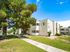Charming apartment complex surrounded by lush greenery, featuring spacious balconies and a welcoming pathway, basking in sunlight.