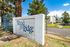 Inviting entrance to Wood Ridge Villas with lush greenery and modern buildings, perfect for comfortable living.
