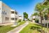 Charming apartment buildings with private balconies and lush green pathways under a bright blue sky.