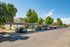 Charming apartment complex with covered parking and lush greenery, featuring a peaceful suburban setting under a bright blue sky.