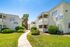Charming apartment complex with sunlit balconies and well-maintained greenery, offering a peaceful living environment.