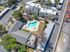 Aerial view of an inviting apartment complex featuring a beautifully designed swimming pool, lush greenery, and modern building architecture.