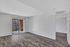 Modern empty apartment with sleek hardwood floors, natural light from large sliding doors, and a private balcony view.