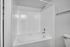 Sleek, modern bathroom featuring a pristine white bathtub with elegant tile surround, ideal for relaxation.