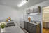 Modern kitchen with sleek gray cabinets, a white refrigerator, and elegant countertop featuring decorative flowers and cutting boards.