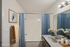 Chic bathroom with elegant blue curtains, a charming bird painting, and fresh floral accents for a serene atmosphere.