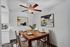 Virtually staged dining room with elegant wooden table, modern art, and sophisticated ceiling fan.