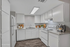 Elegant modern kitchen with sleek white cabinetry, stainless steel appliances, and chic wood flooring, offering a bright and inviting space for culinary creativity.