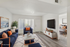 Inviting living room with modern decor, cozy navy sofas, and sleek wooden flooring, leading to a stylishly staged bedroom.