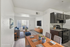 Bright, virtually staged open-plan living and kitchen area with modern d&eacute;cor, featuring sleek black cabinetry and elegant furnishings.