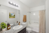 Modern bathroom with elegant granite countertop, stylish fixtures, potted plant, and serene wall art.