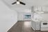 Welcoming open-concept apartment with sleek wood flooring, modern kitchen, and ample natural light from a large window.