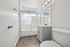 Bright modern bathroom with crisp white cabinetry, enclosed shower, and wood-style flooring, offering a sleek and refreshing ambiance.